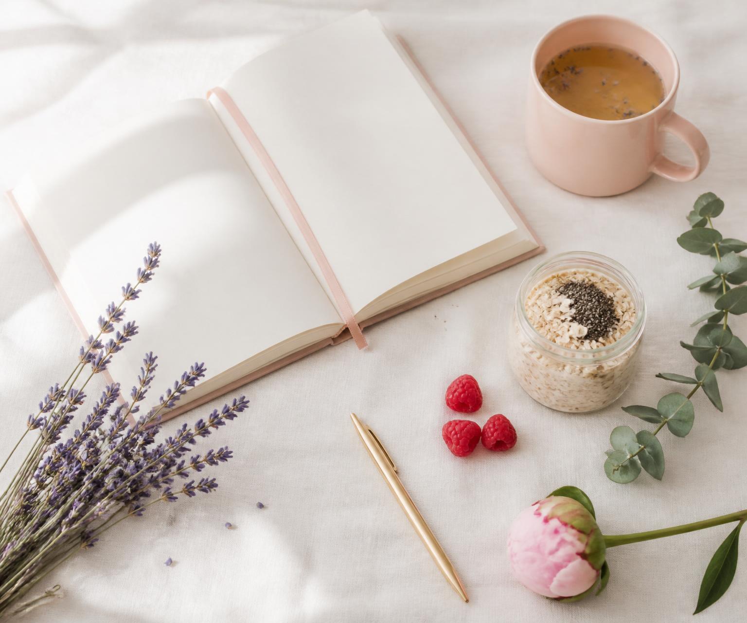 A soft flat-lay of an open journal, lavender, tea and oats